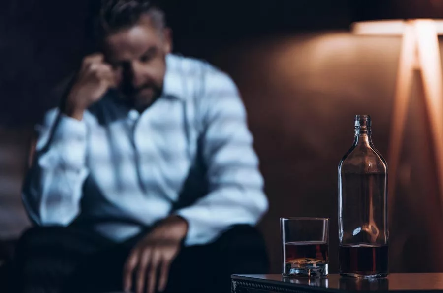 A man ponders his next drink, not knowing an alcohol rehab Albuquerque exists that accepts Blue Cross Blue Shield for rehab in Icarus Behavioral Health