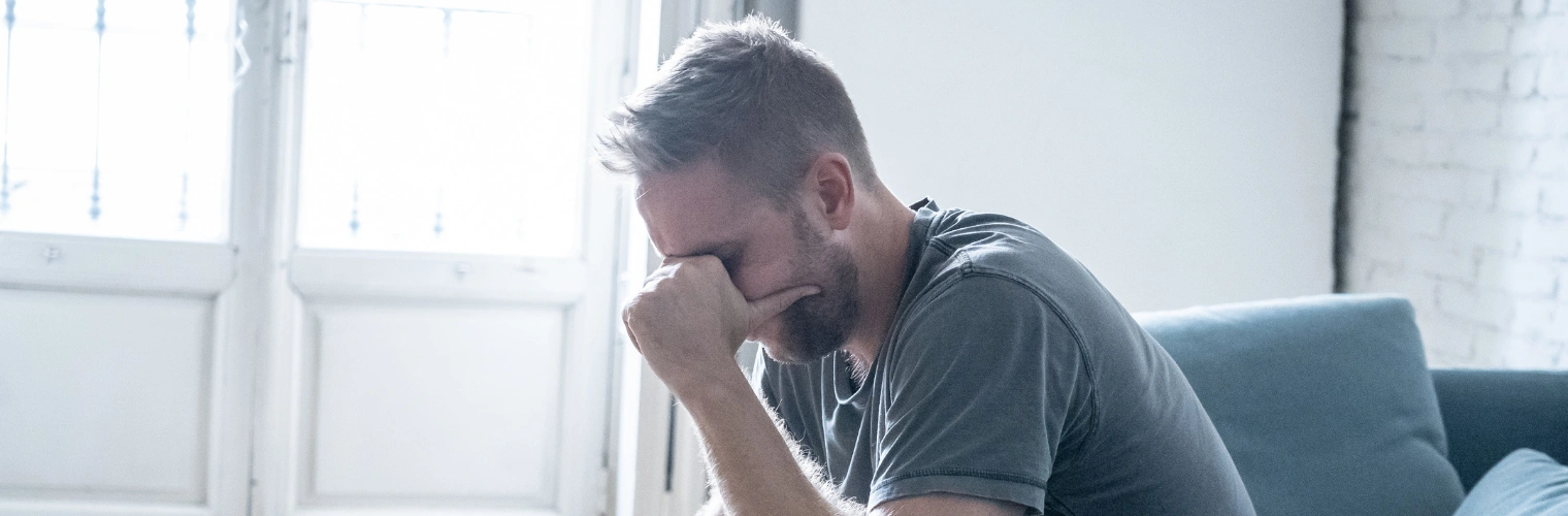 Man sitting alone holding hands on his face - Is PTSD A Disability in New Mexico and the US - Icarus Recovery Center