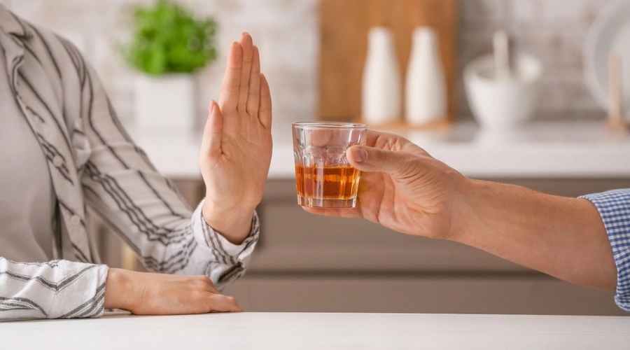 Image of a man holding a glass of whiskey with a woman's hand out telling him to stop - Manage Alcohol Consumption with BPH
