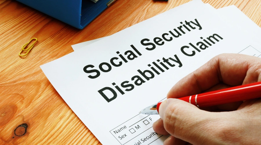 Person's hand holding a pen and filling out an Social Security form - SSDI Benefits for Post-Traumatic Stress Disorder