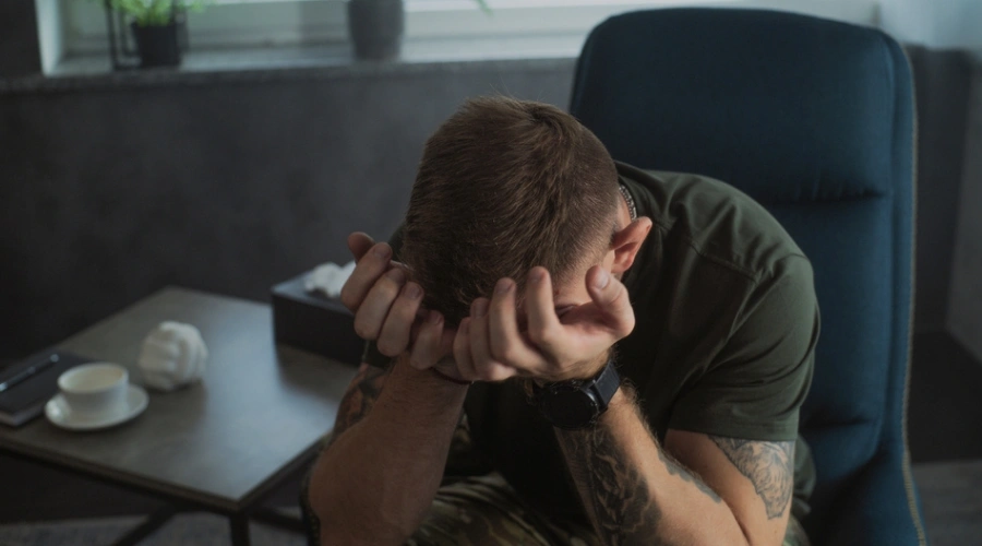 Man sitting in dark with with hands on his face - What is Post-Traumatic Stress Disorder