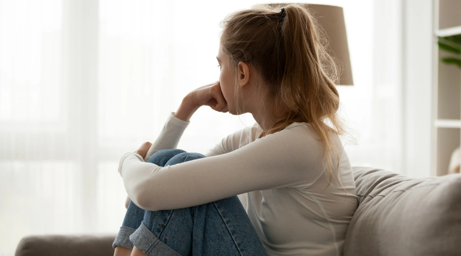 Image of a frustrated  female sitting on a sofa  - Symptoms of Complex PTSD